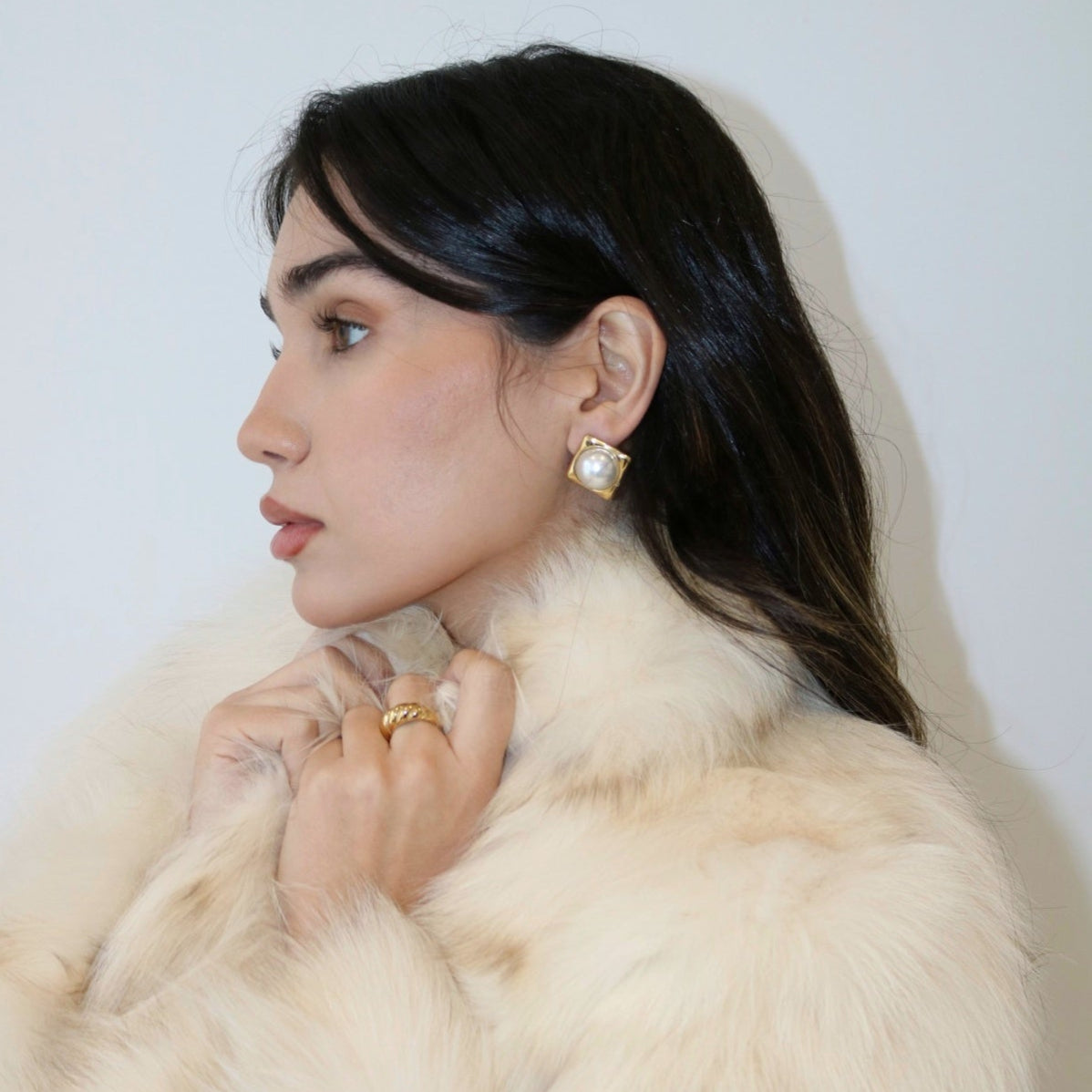 Woman wearing Celeste Pearl Statement Earring in a beige fur coat
