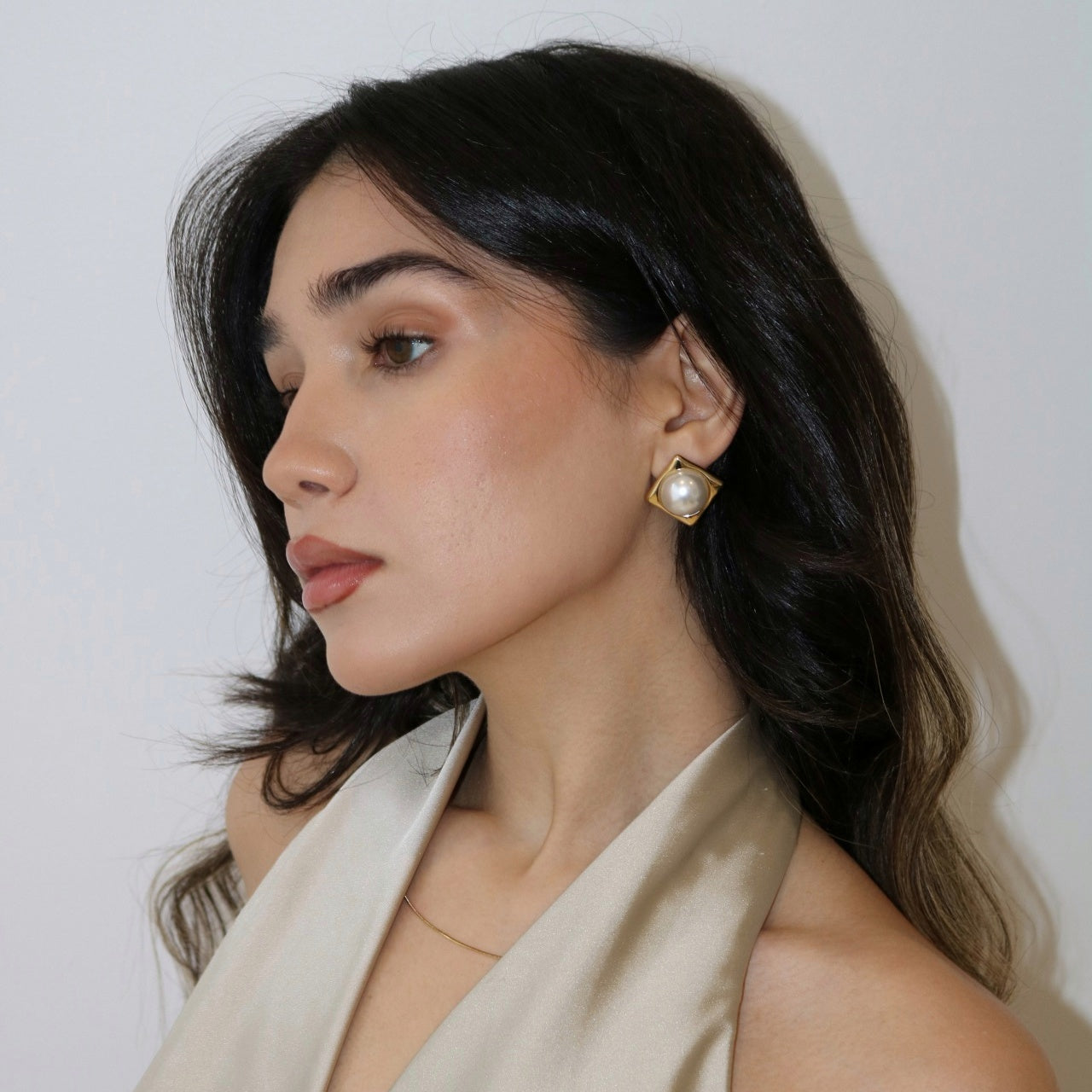 Woman wearing Celeste Pearl Statement Earring in a beige silk halter top