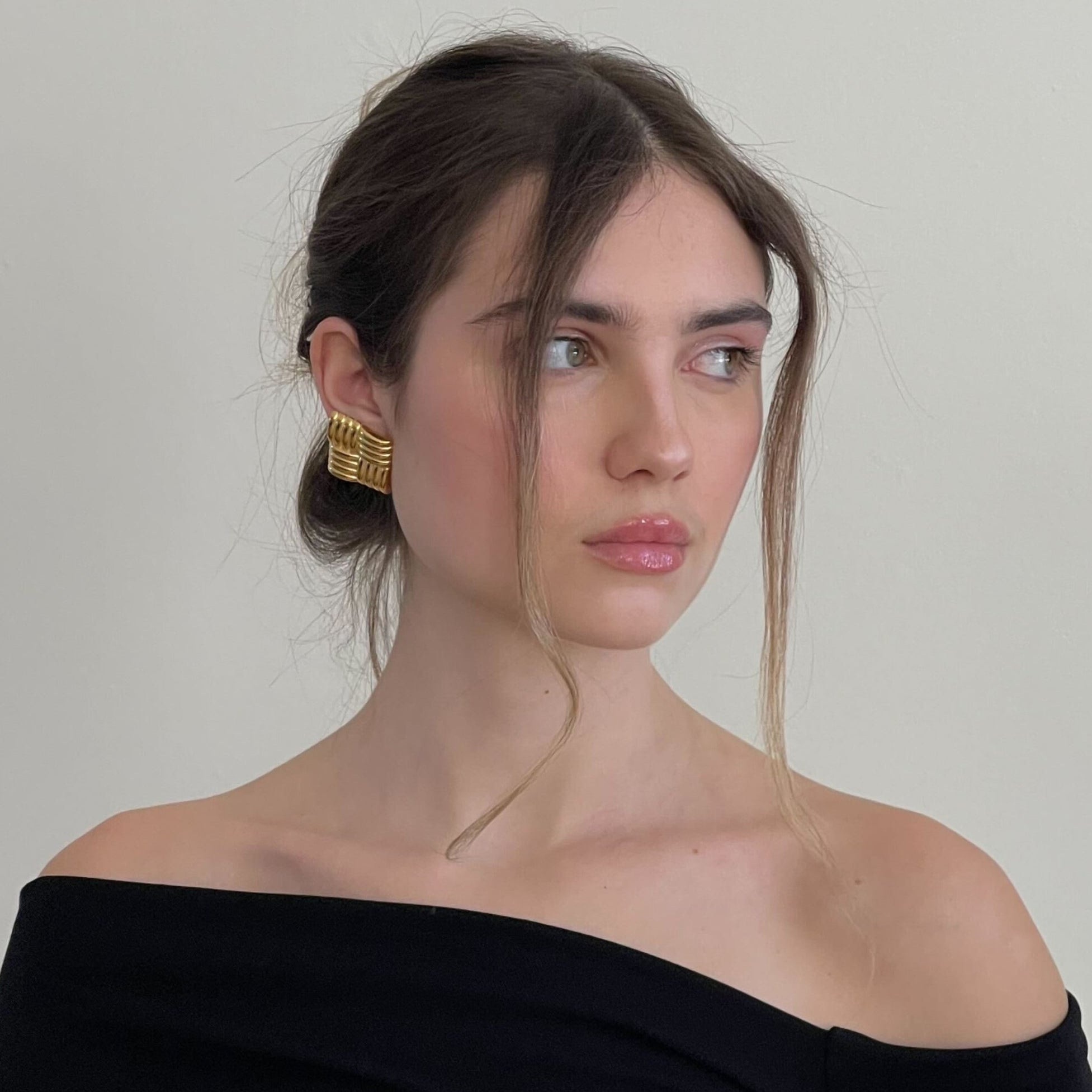 Woman wearing gold statement earrings and a black top.