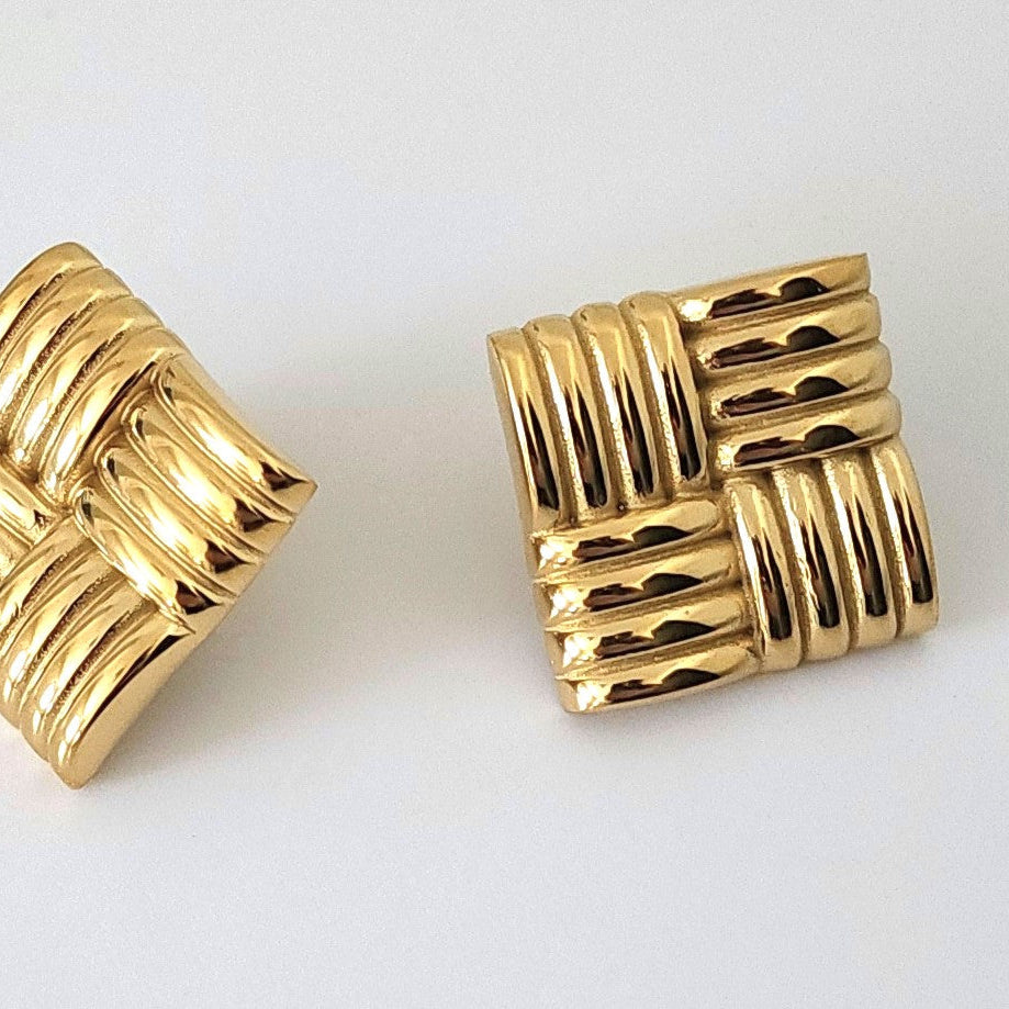 Pair of gold earrings with a woven design on a white background