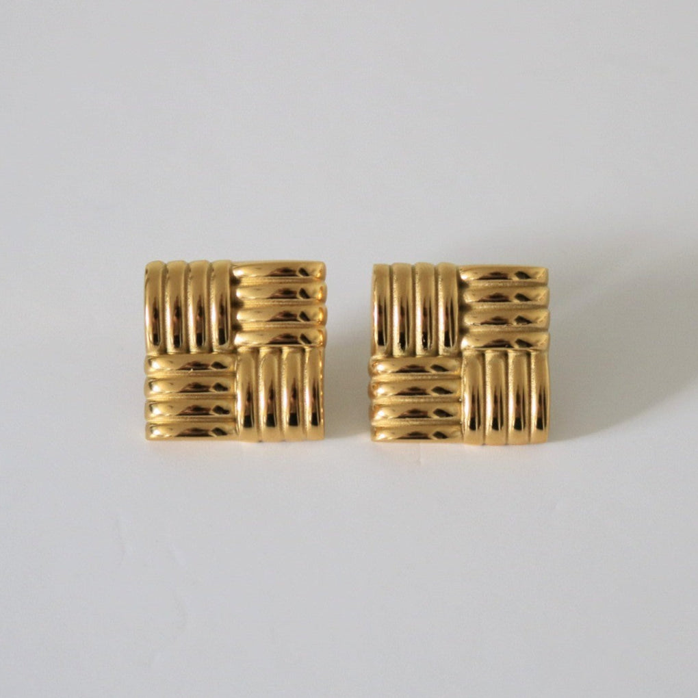 Pair of gold textured square earrings on a light gray background