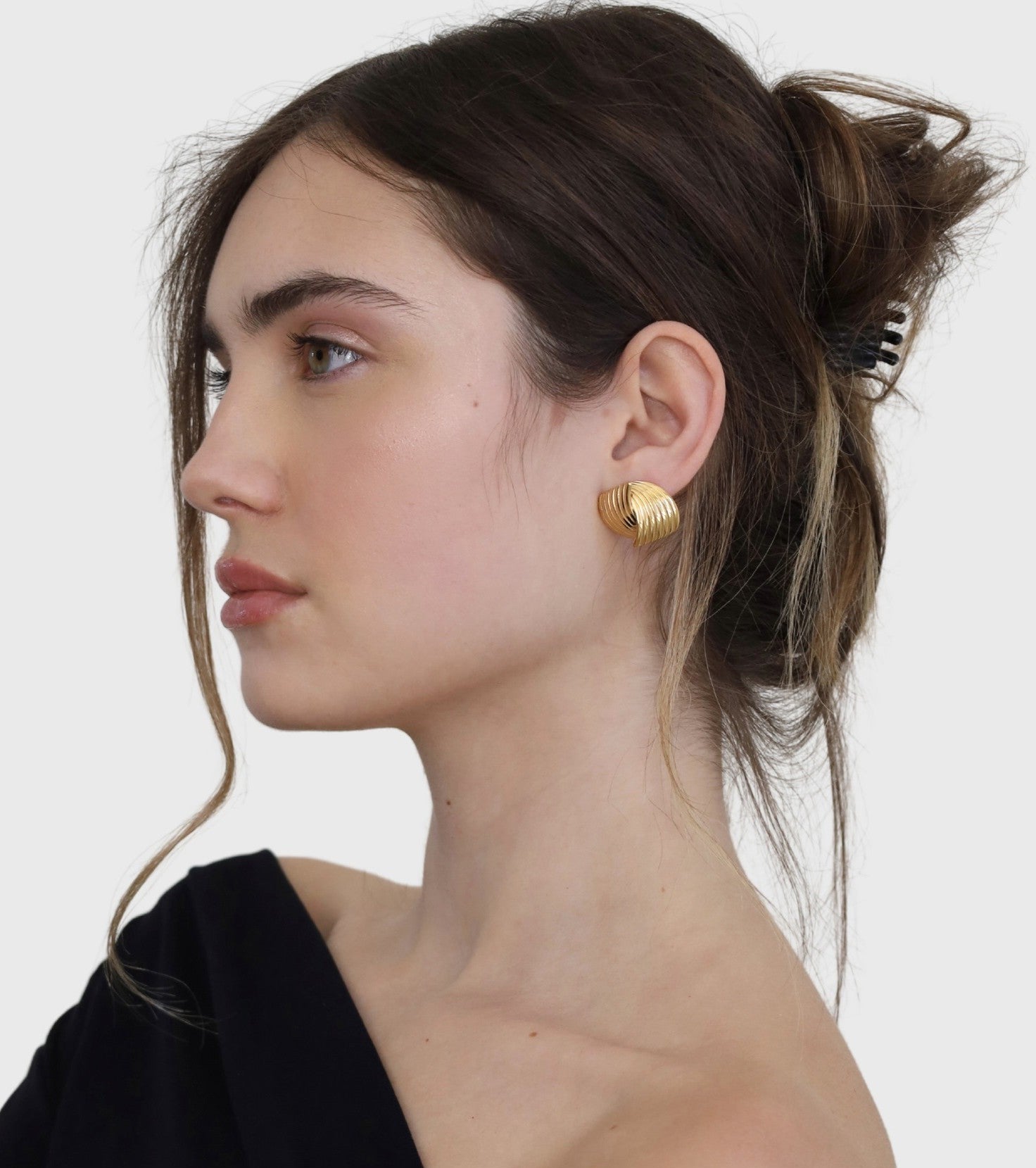 Woman wearing gold hoop earrings against a white background