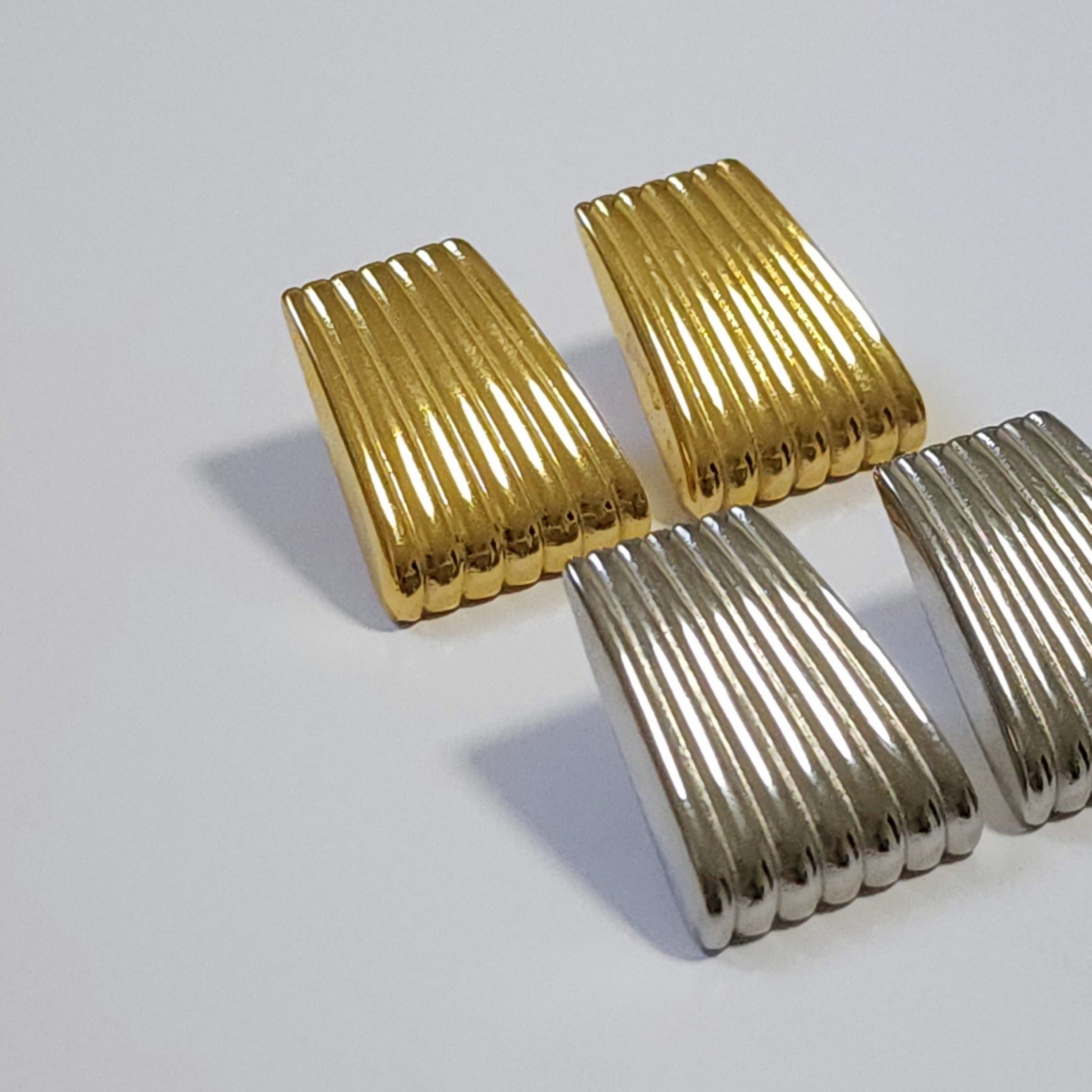 Gold and silver vintage statement earrings on a light grey background.