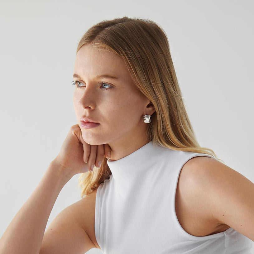 Woman wearing Gabriel Abstract Hoop Earrings in silver with a white tank top