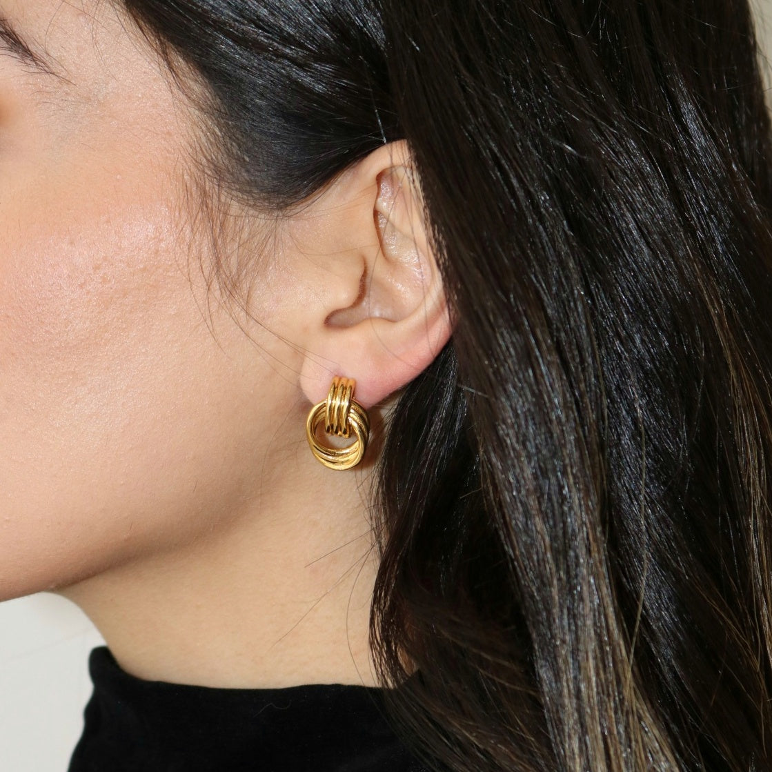 Close up detail shot of gold vintage knot earrings on woman.
