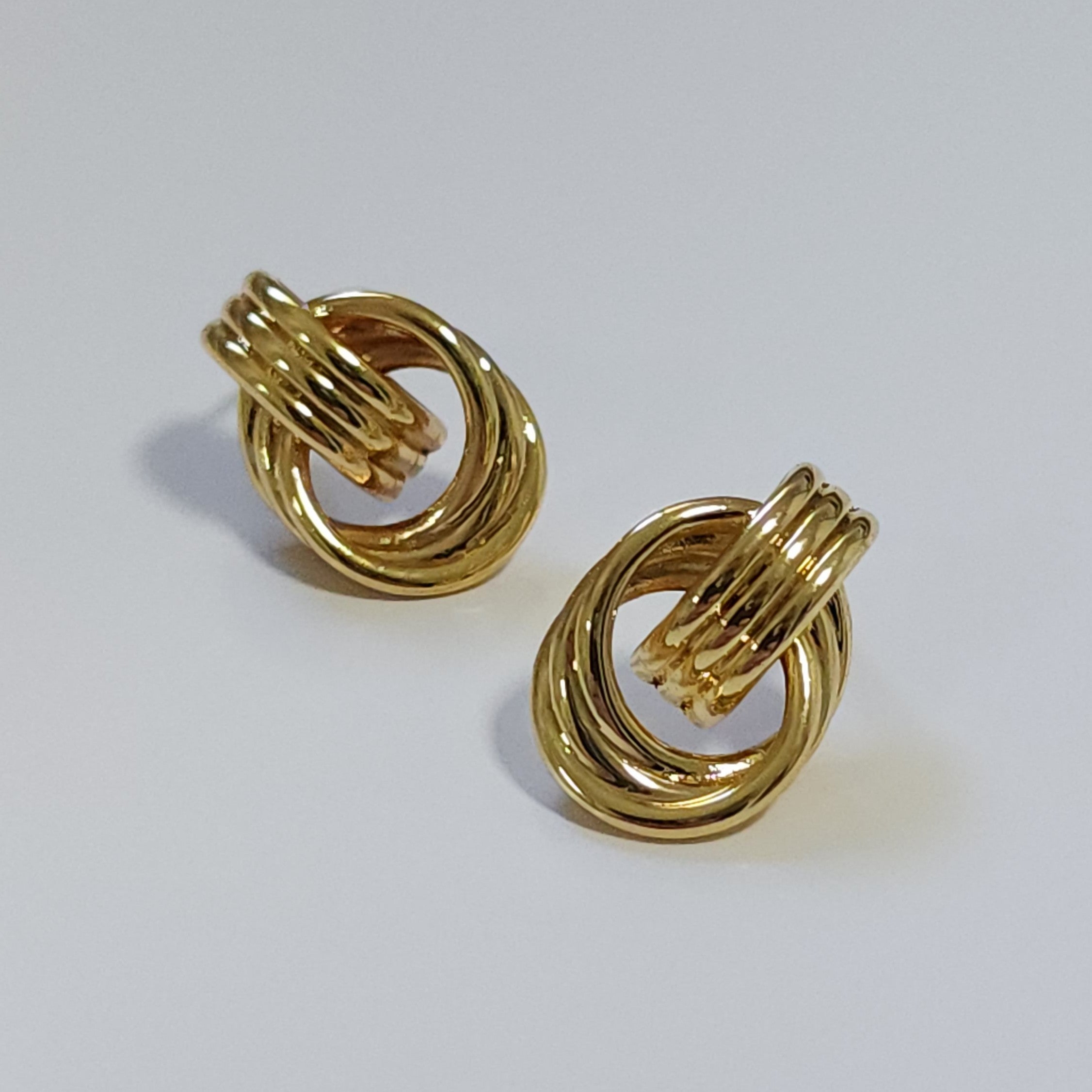 Pair of gold vintage knot earrings on a light gray background
