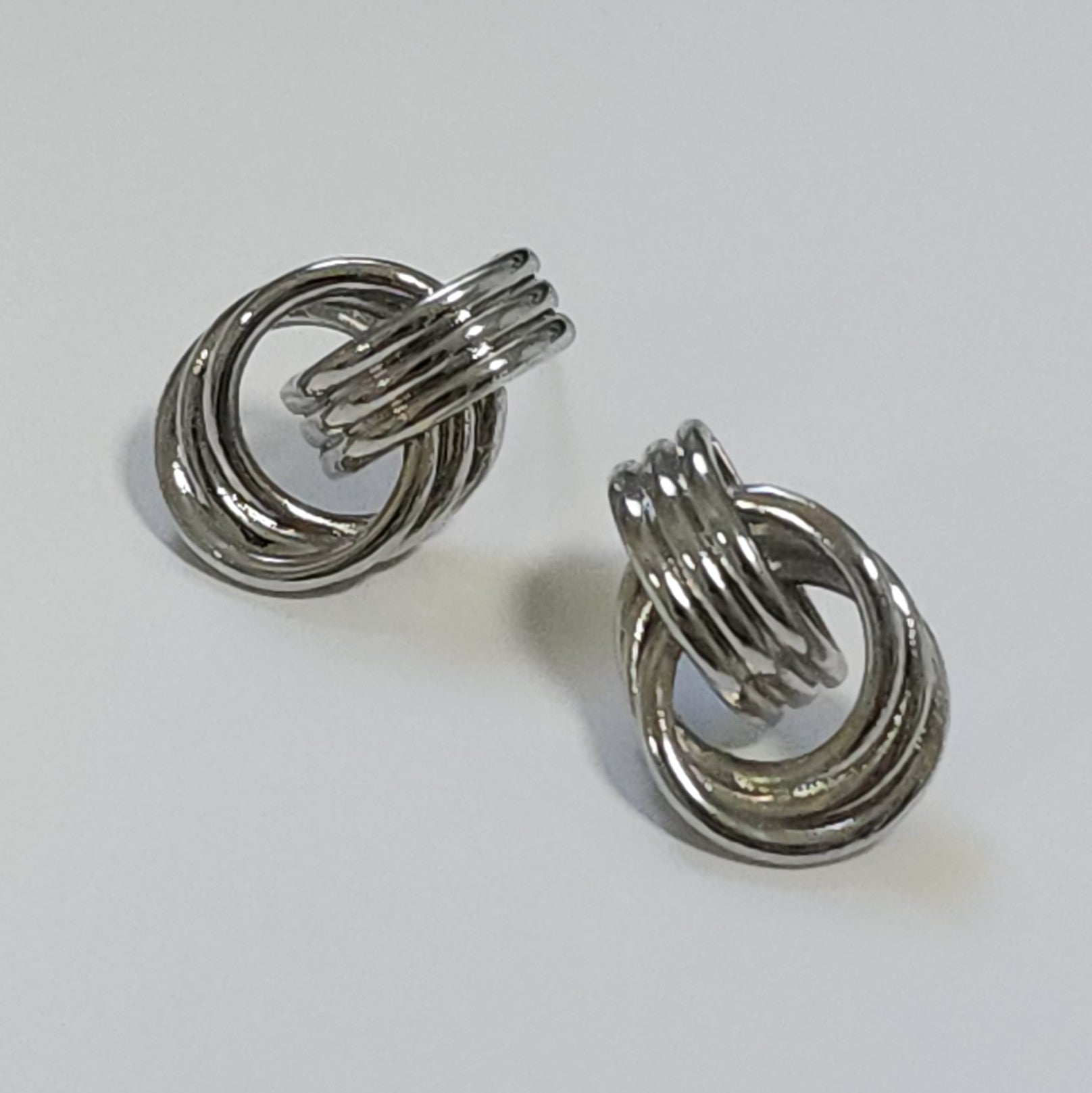 Pair of silver vintage knot earrings on a light gray background