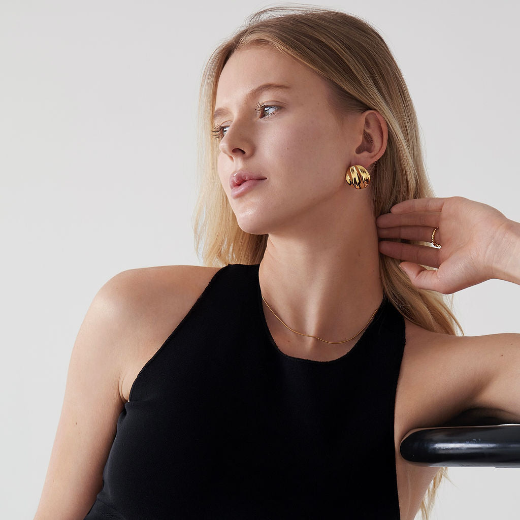 Woman wearing Mae Round Statement Earrings with a black tank top on a light background