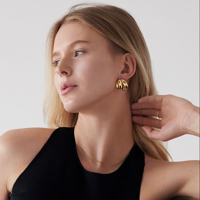 Woman wearing Mae Round Statement Earrings with a black tank top on a light background