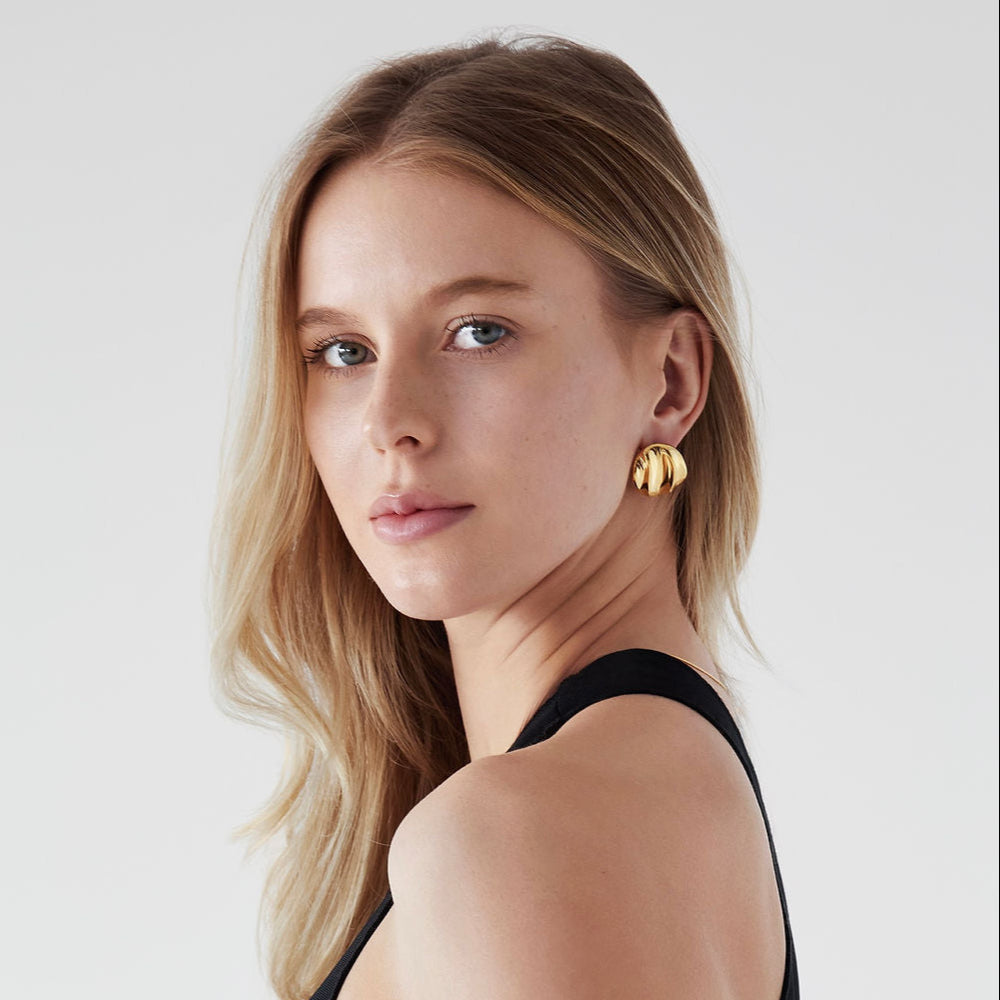Woman wearing a black sleeveless top with Mae Round Statement Earrings on a light background