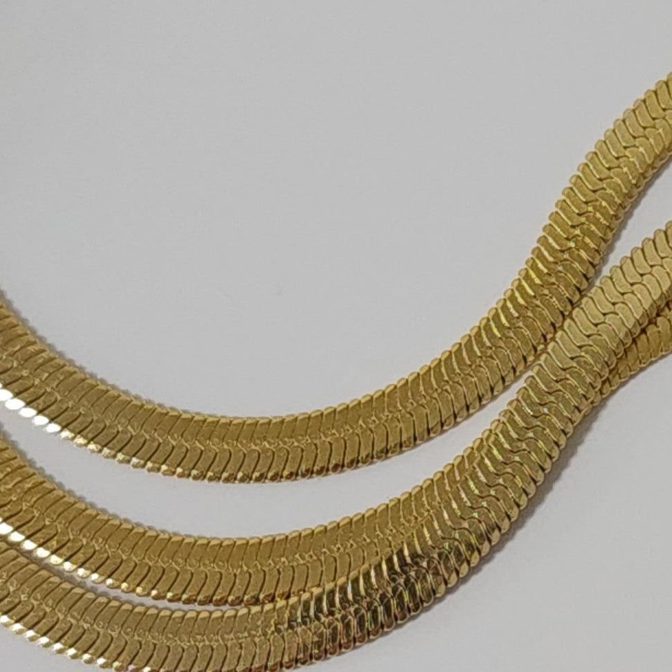 Gold snake chain on a light gray background