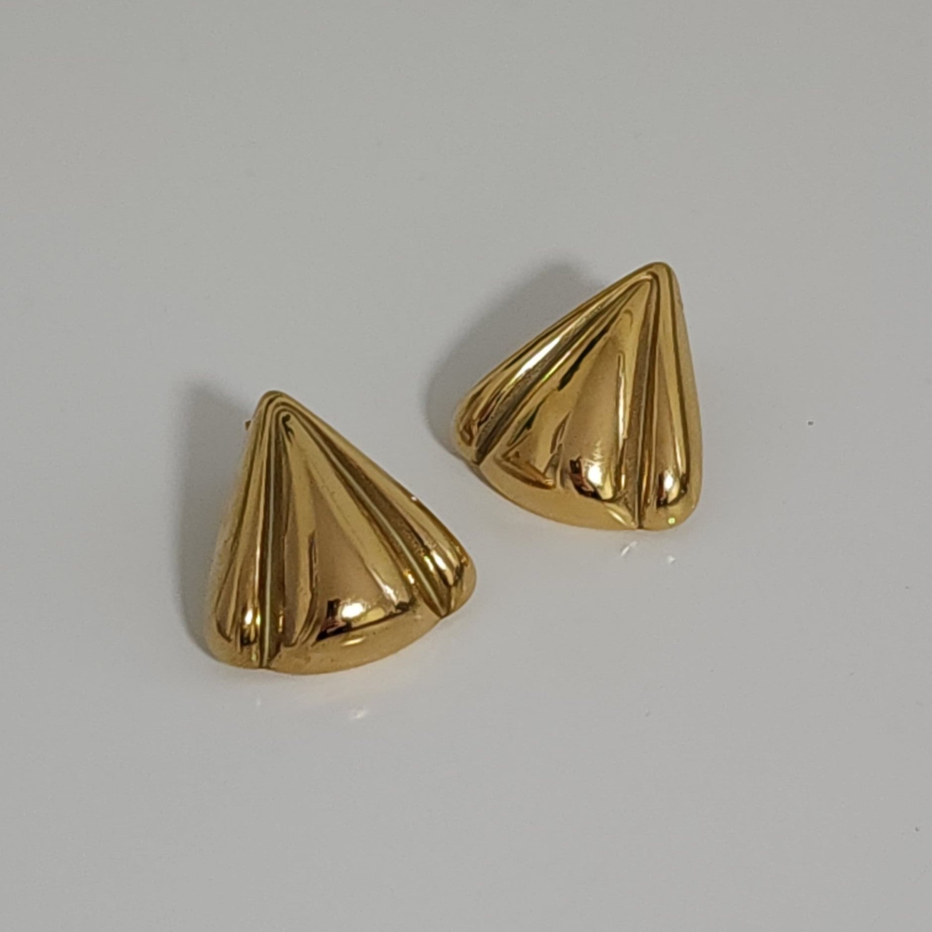 Pair of gold petal-shaped earrings on a light gray background