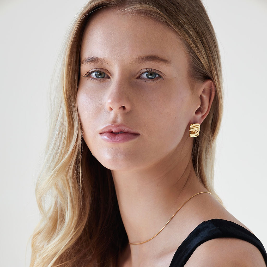 Woman wearing Rochelle Dainty Square Stud Earrings in gold with a black tank top and dainty gold necklace