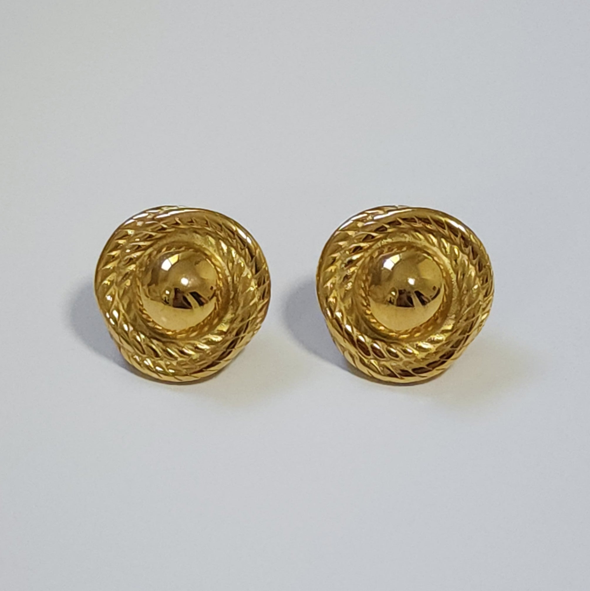 Pair of gold vintage statement earrings on a light gray background