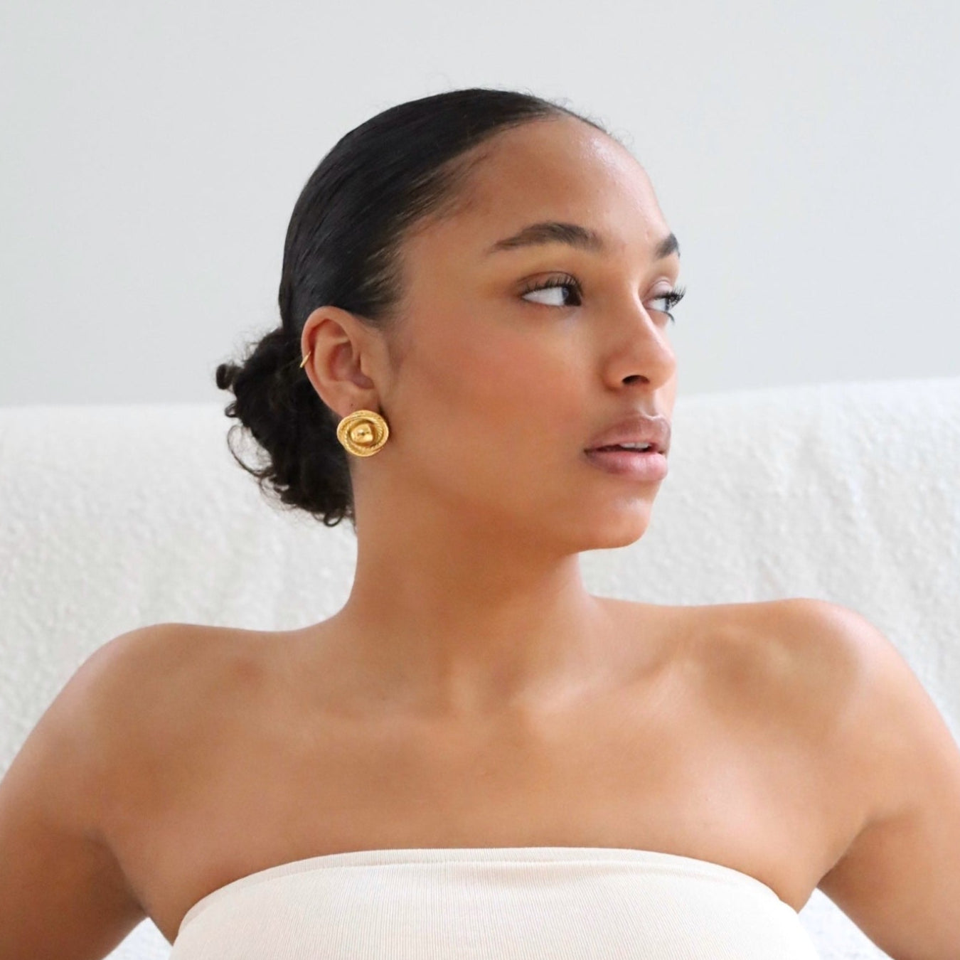 Woman wearing gold vintage statement earrings.