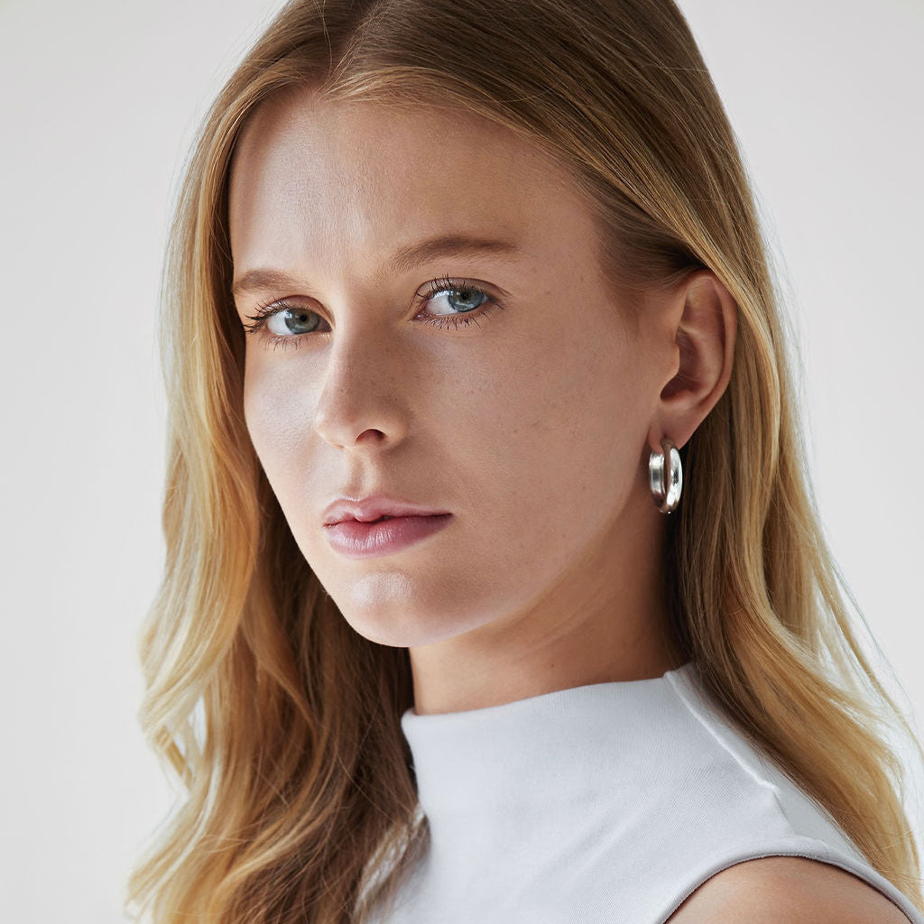 Woman wearing Sylvie Classic Hoop Earrings in silver with white tank top