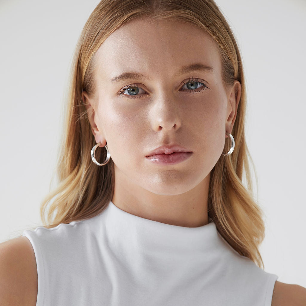 Woman wearing Sylvie Classic Hoop Earrings in silver with white tank top