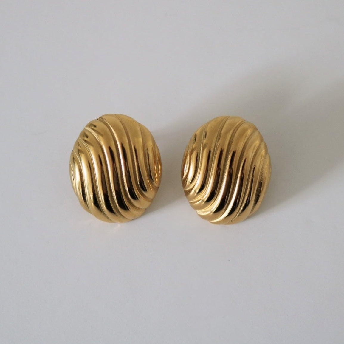 Pair of gold statement earrings on a light gray background