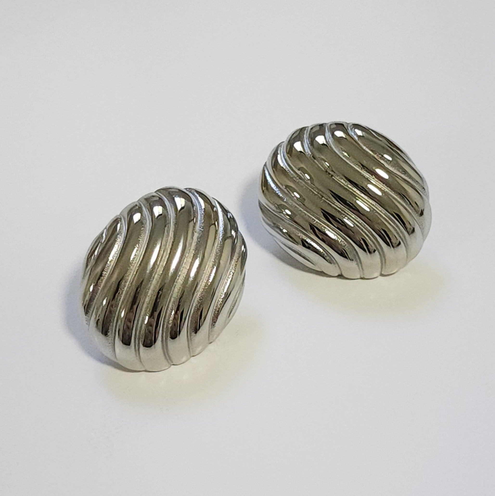 Pair of silver statement round earrings on a light gray background