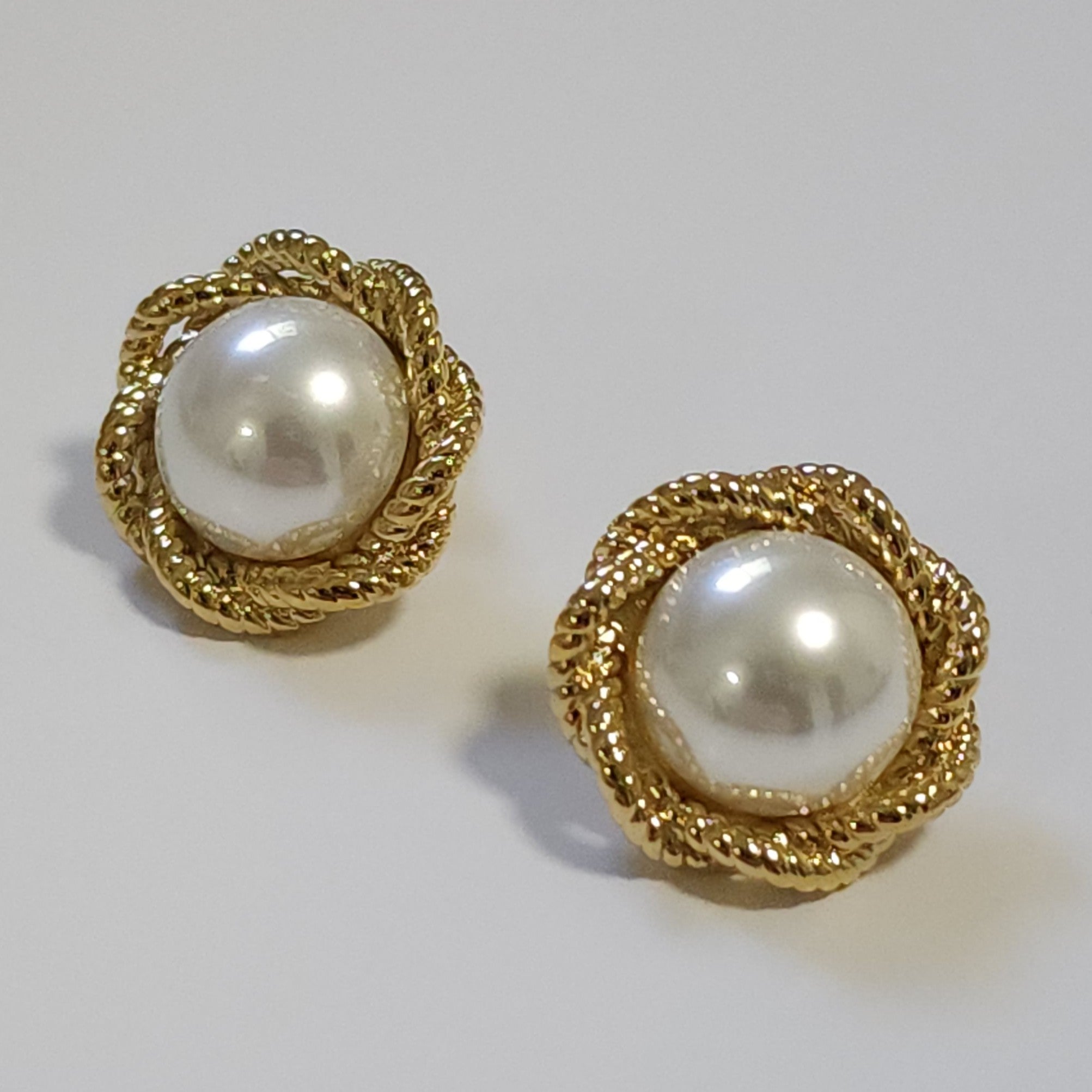 Pair of pearl vintage earrings on a light grey background.
