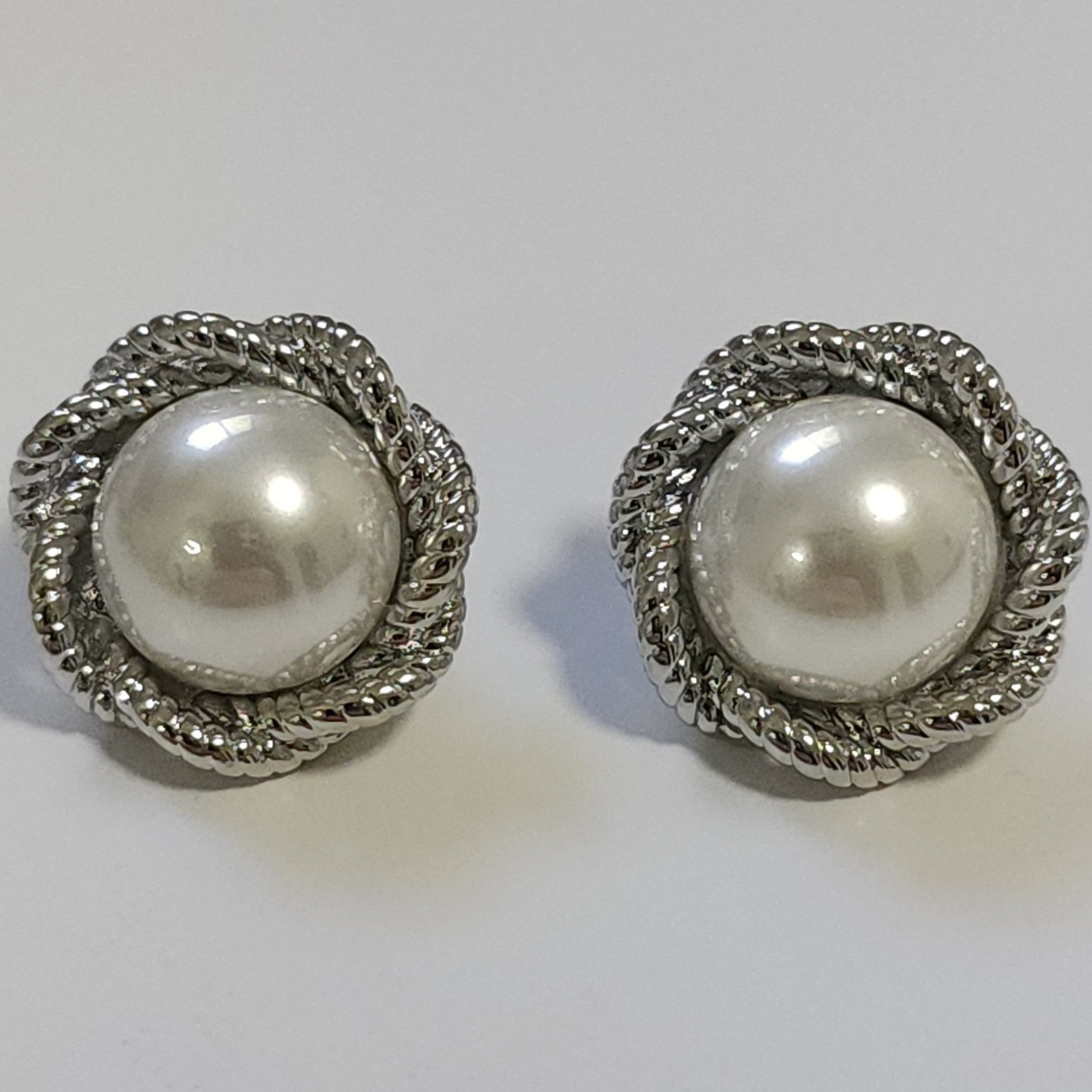 Pair of silver and pearl vintage statement earrings on a light grey background.