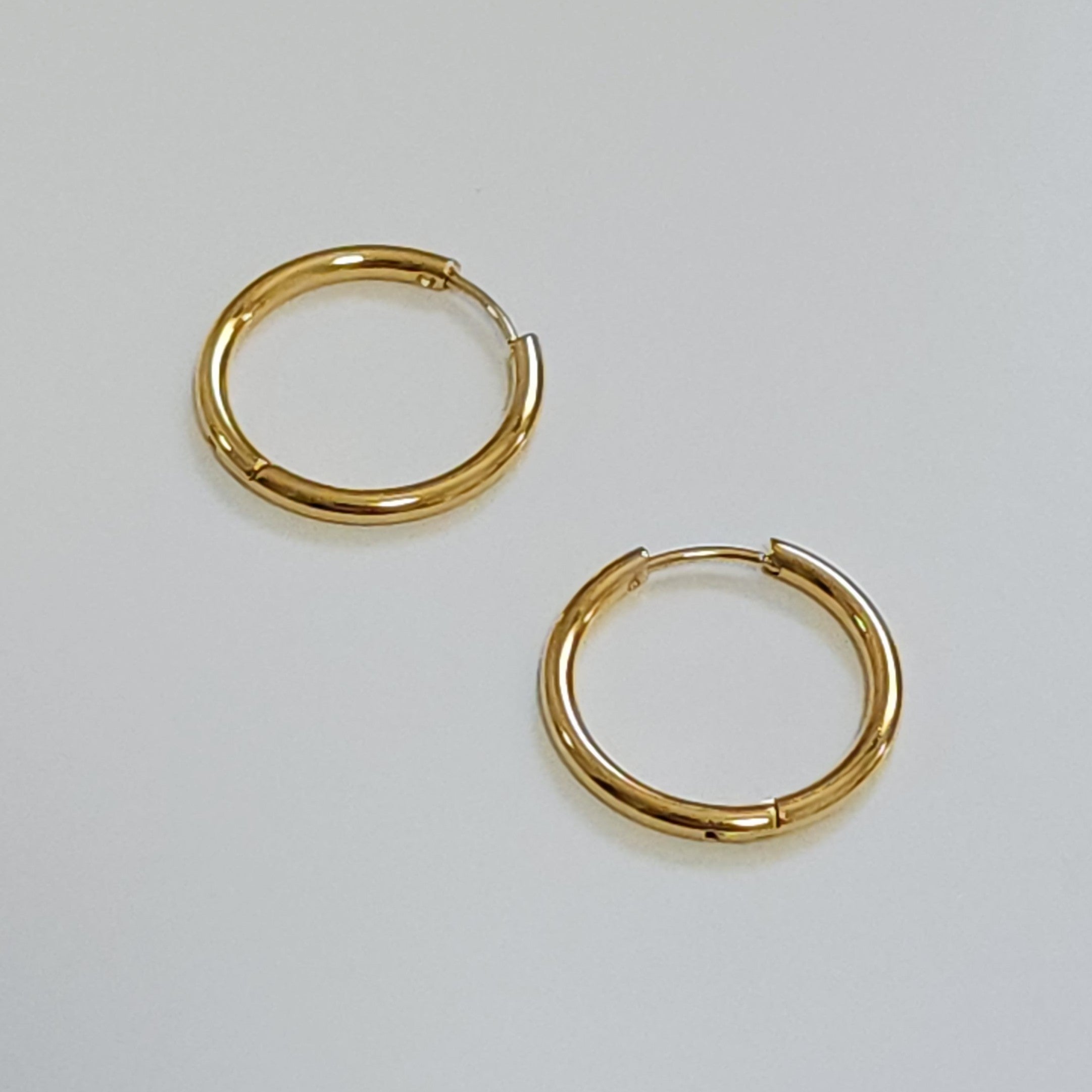 Gold hoop earrings on a light gray background