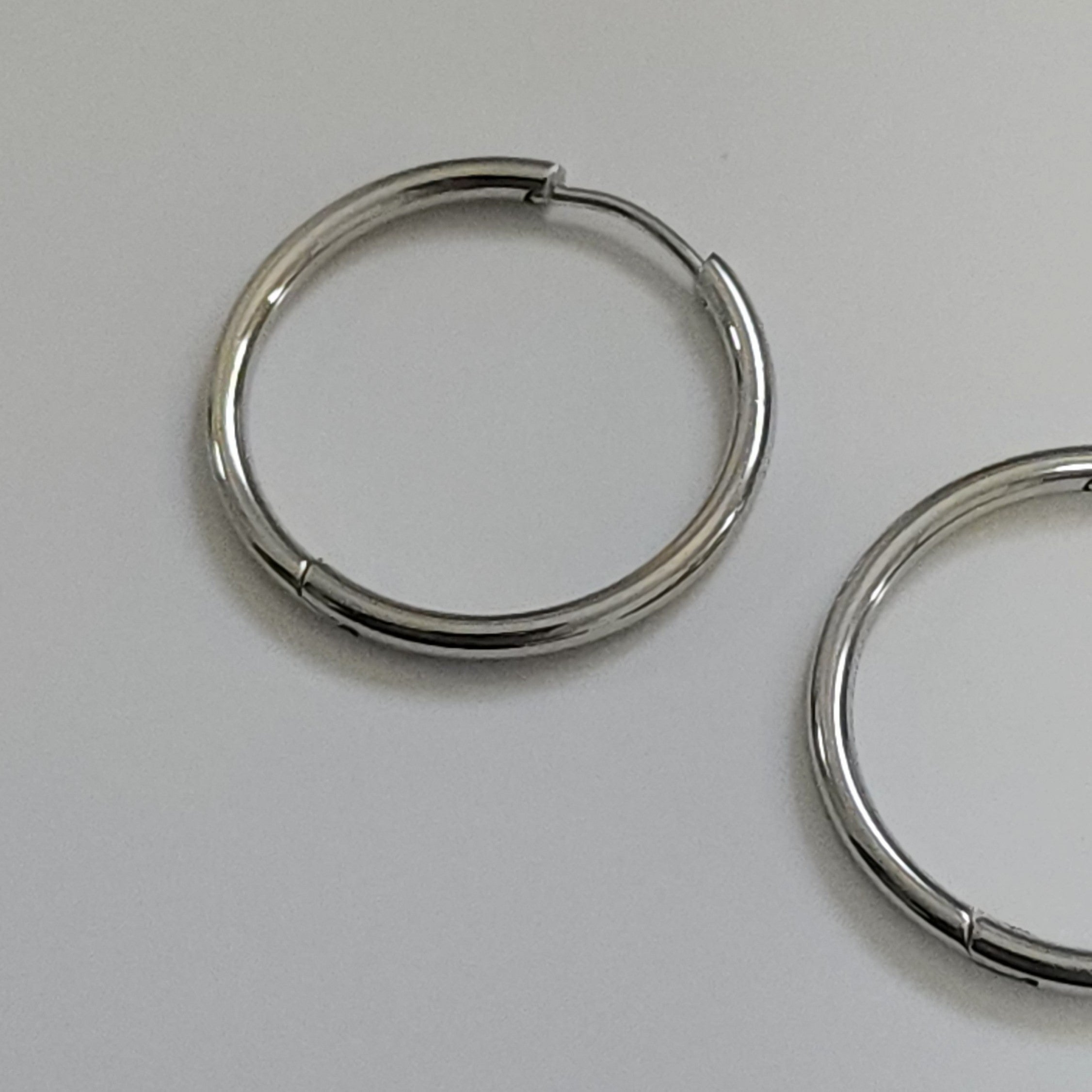 Pair of silver hoop earrings on a light gray background