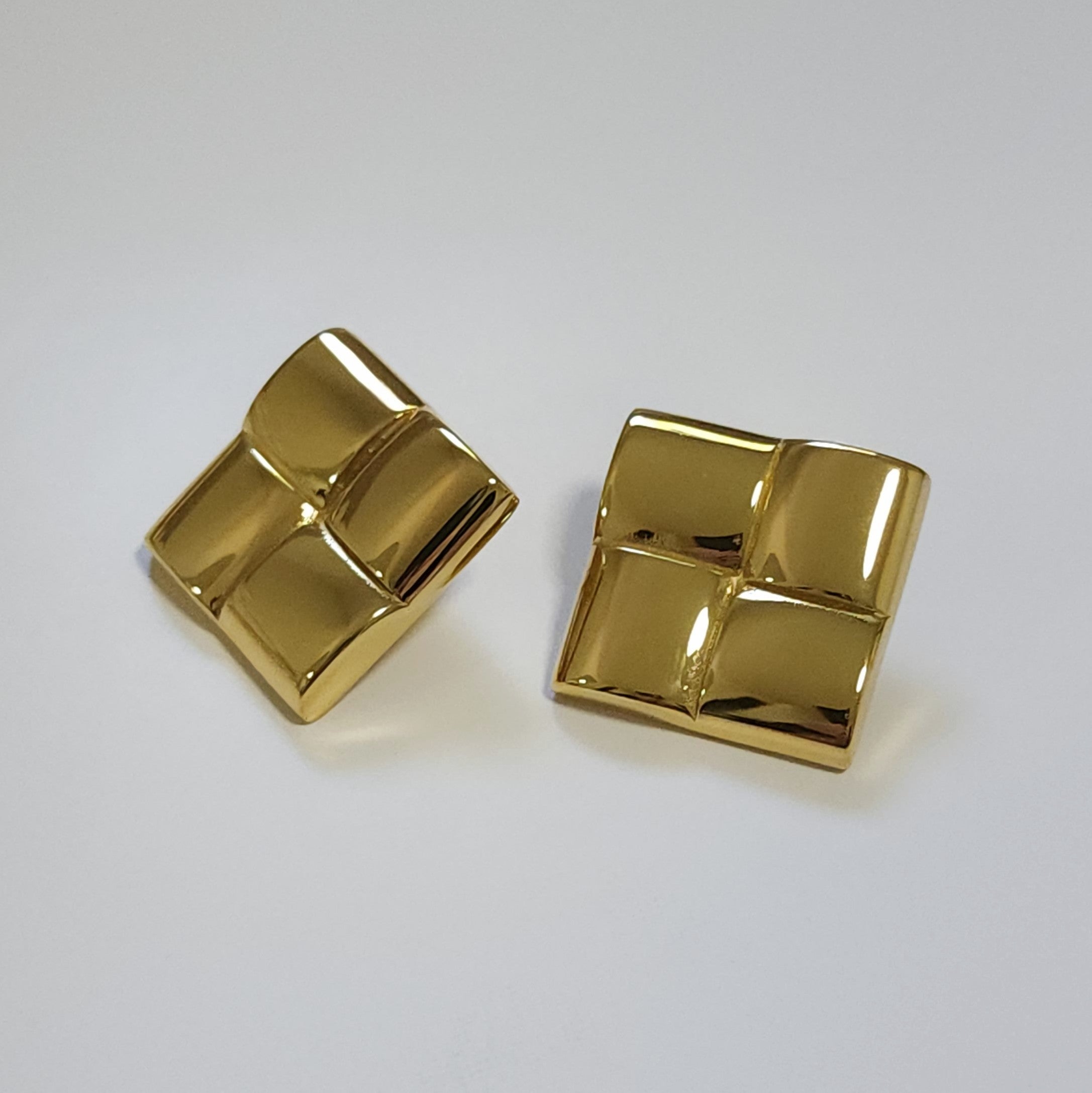 Pair of gold square earrings on a light gray background
