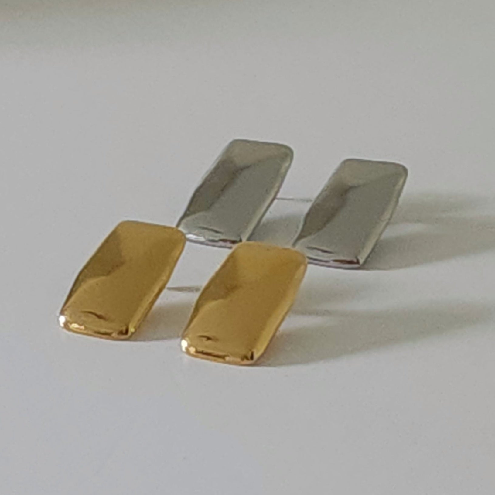 Pair of gold and silver earrings on a light gray background