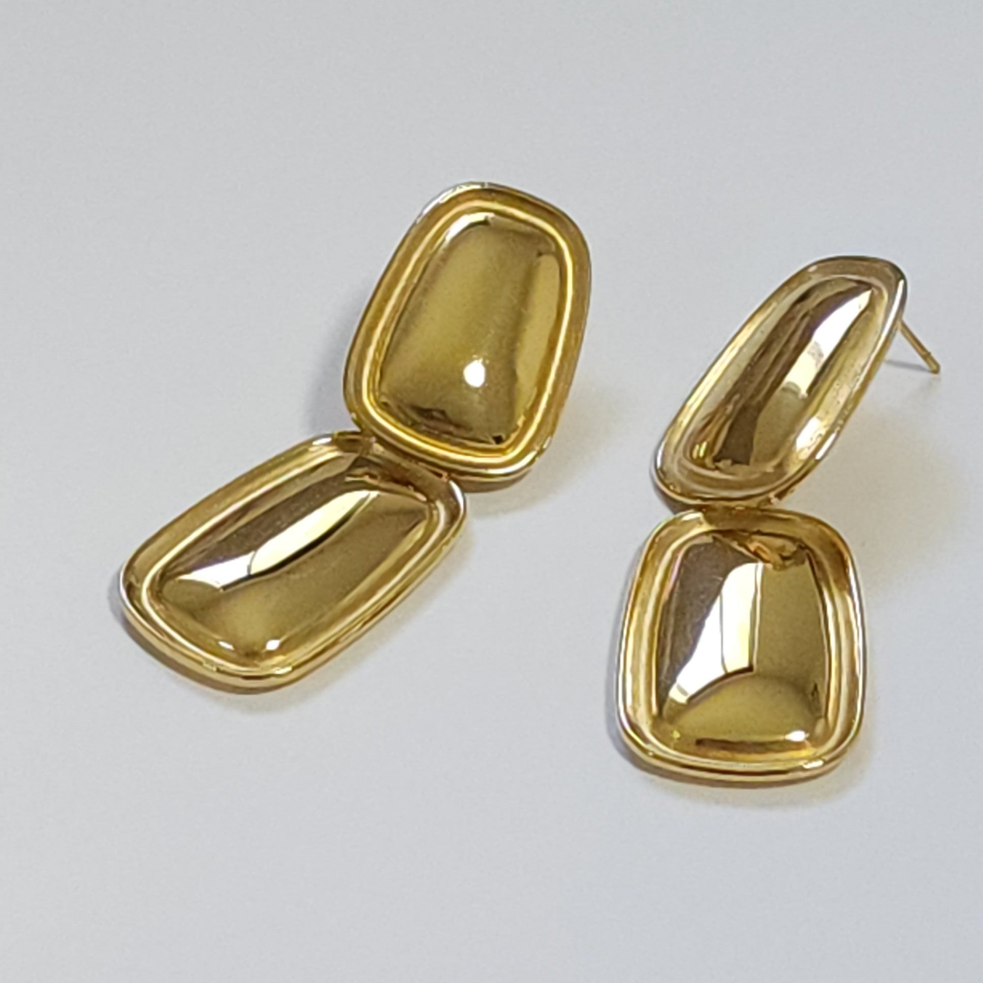 Pair of gold earrings on a light gray background